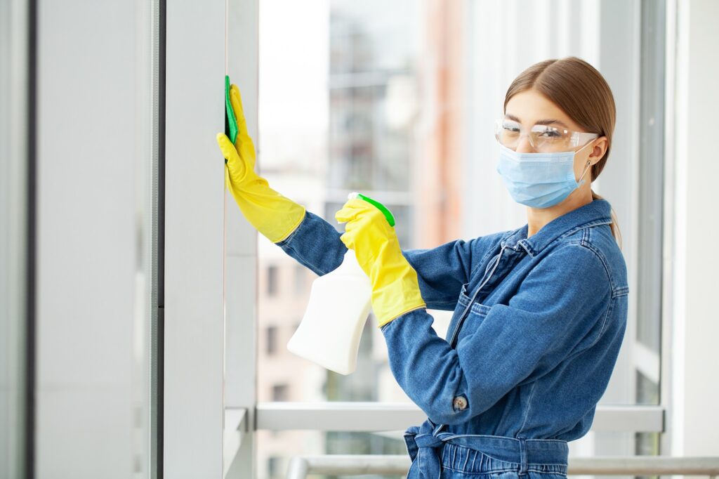 Woman professional cleaner in protective medical mask cleaning office